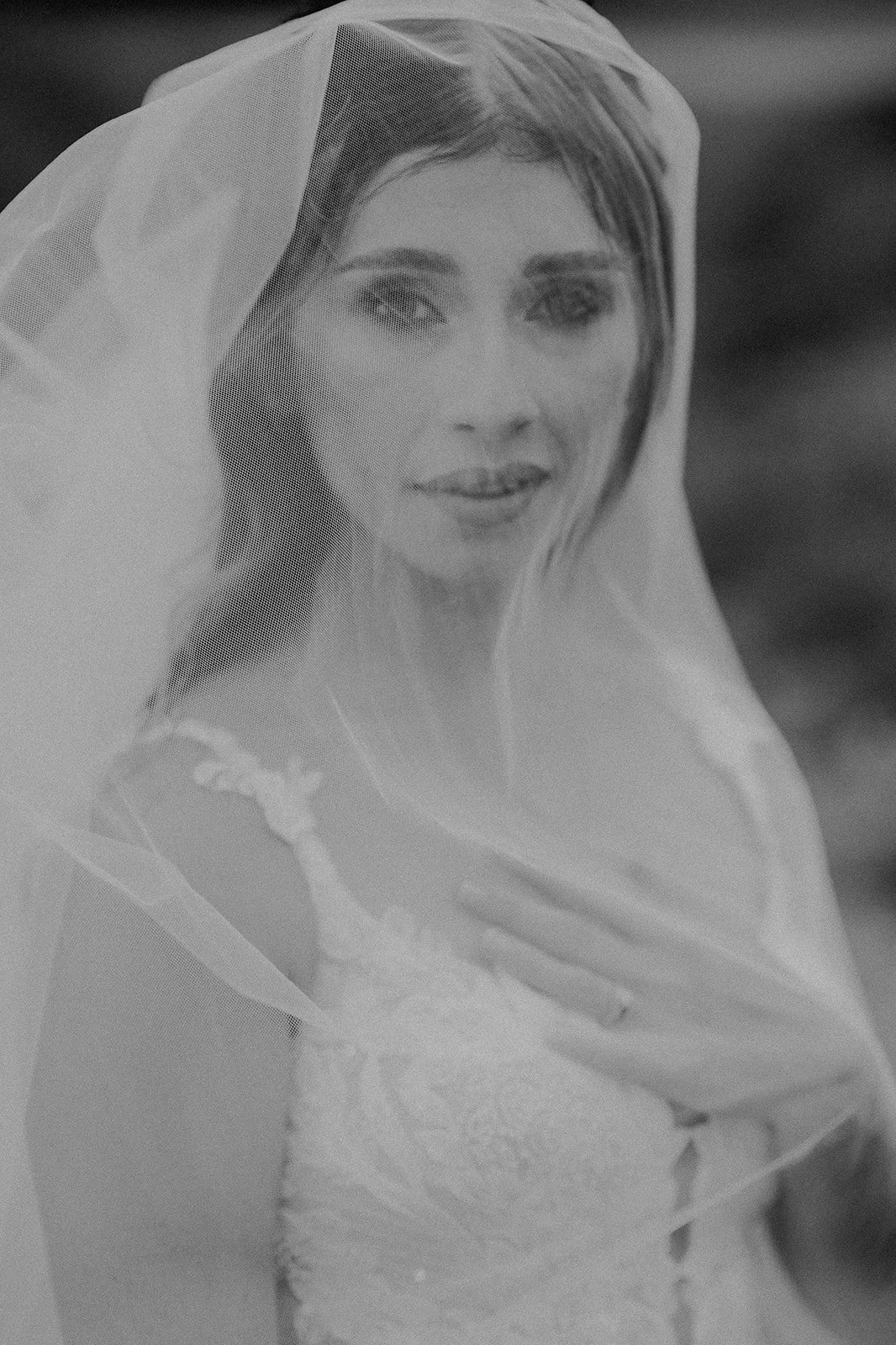 Retrato en blanco y negro de una mujer con vestido de novia y velo, sonriendo suavemente.