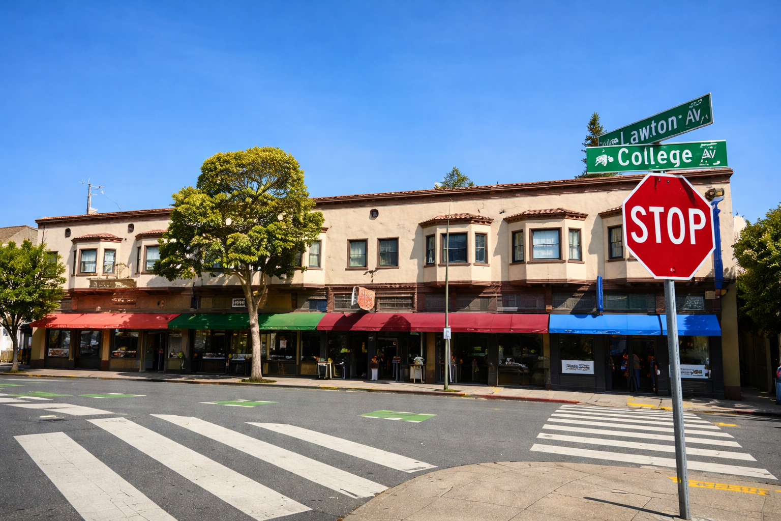 Street view with a storefront, a stop sign, street signs for Lawton Avenue and College Avenue, a pedestrian crosswalk, and trees against a clear blue sky.