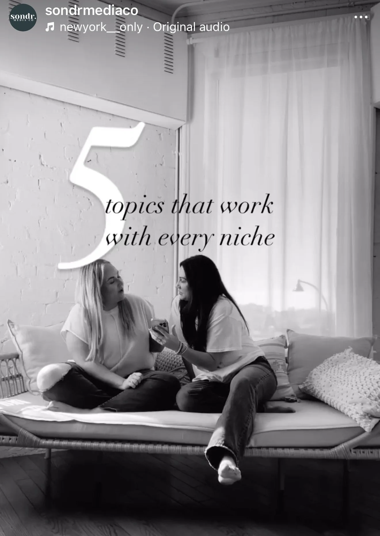 Two women sitting on a bed, one holding a phone. The room has white brick walls, a window with sheer curtains, and pillows. Overlaid text reads '5 topics that work with every niche'.