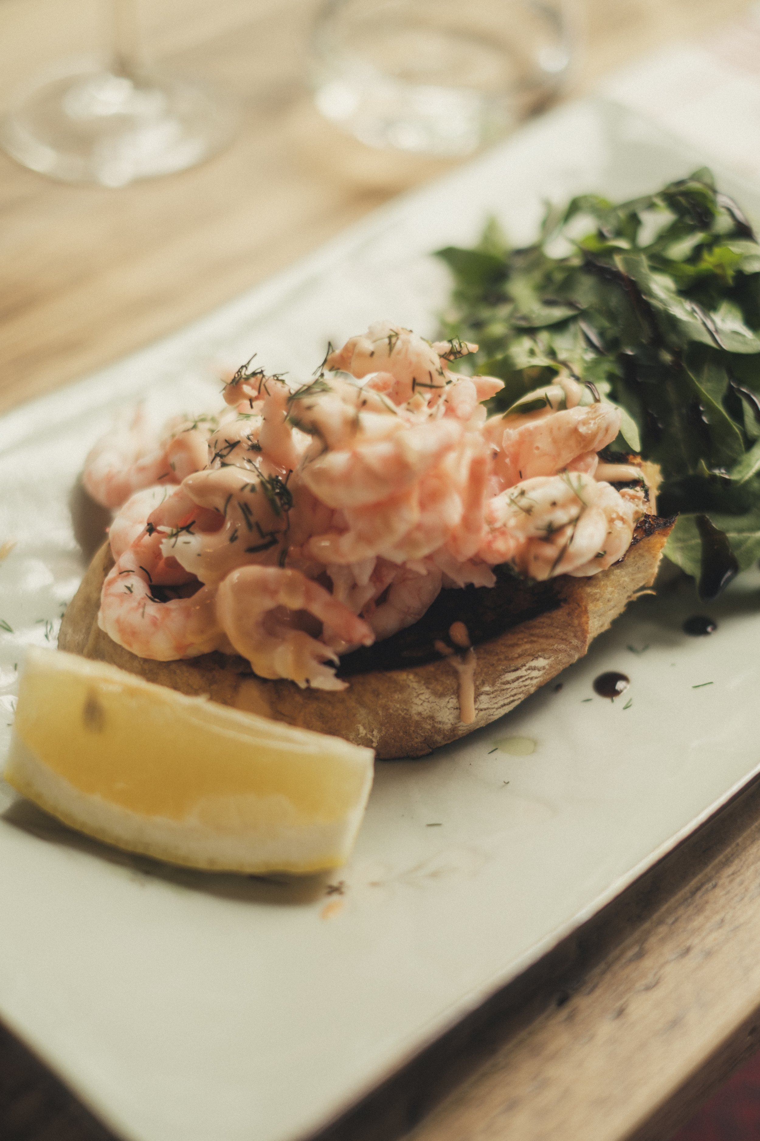 Klassisk rekesmørbrød med majones og salat på landbrød, servert på hvit tallerken med sitron og salat - Bygdøy Vertshus.