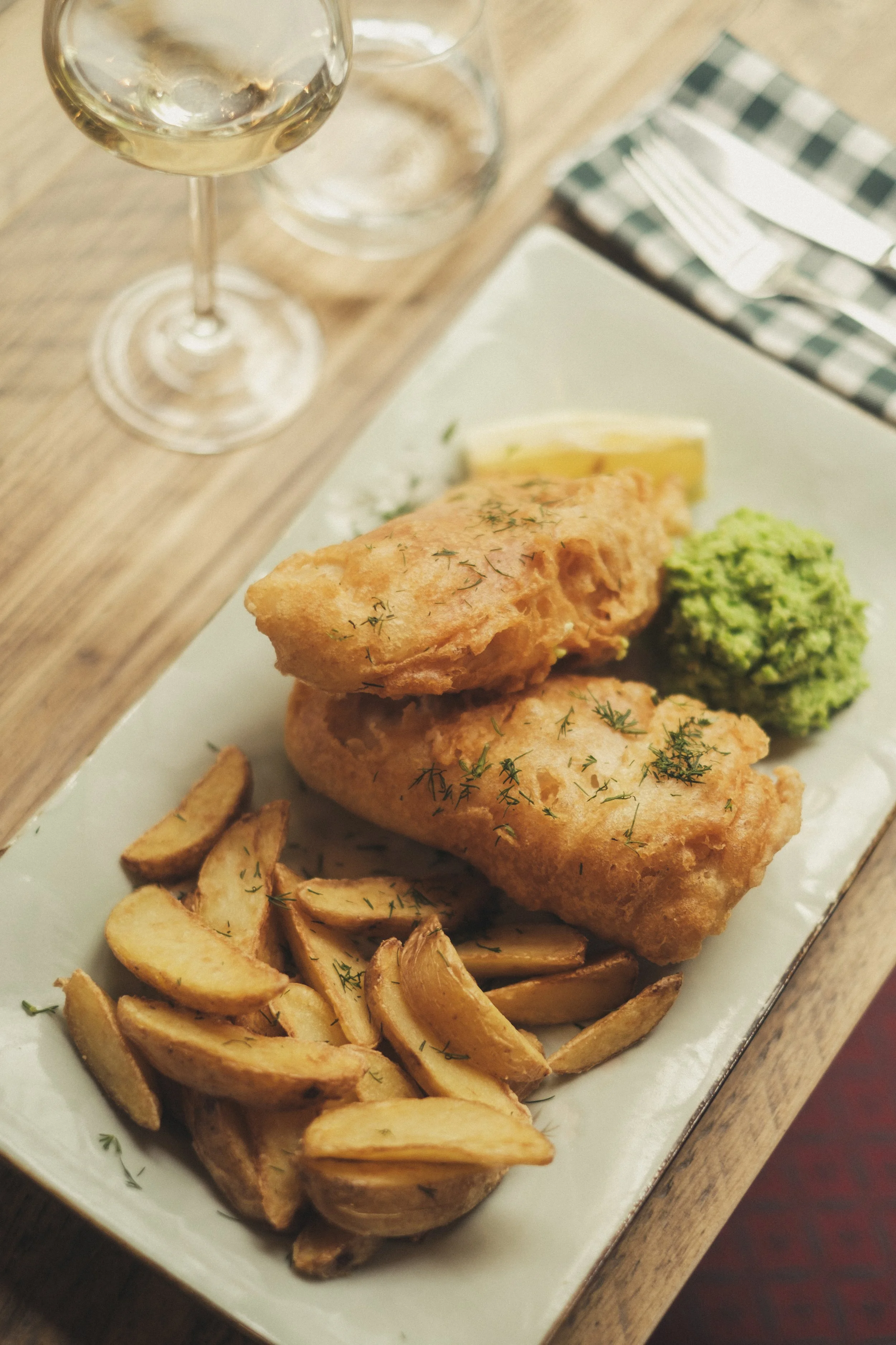 Fish and chips - ertestuing og fisk servert med fries på hvit tallerken - Bygdøy Vertshus.