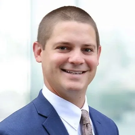 A man in a blue suit smiling at the camera.