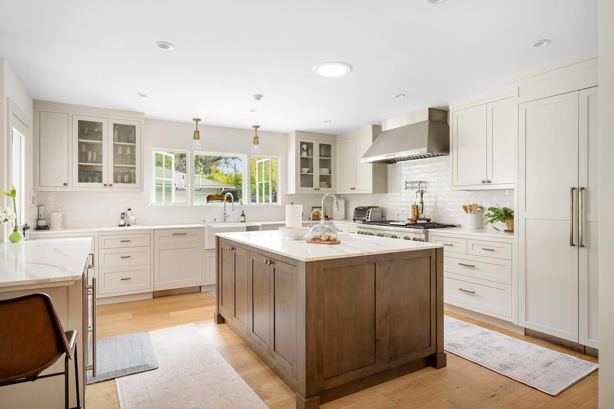 A spatial reconfiguration opening the kitchen and family room toward a new bricked terrace