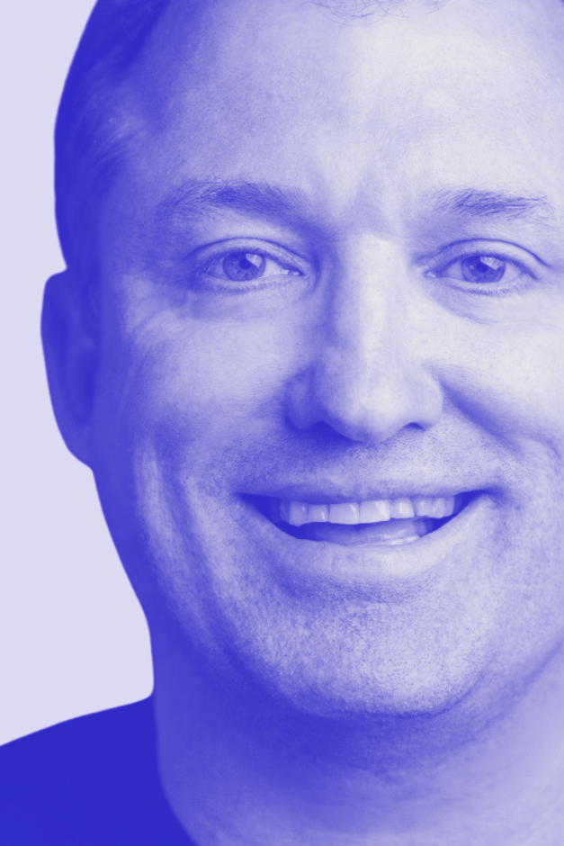 Close-up portrait of a smiling man with short hair, shown in a blue color overlay.