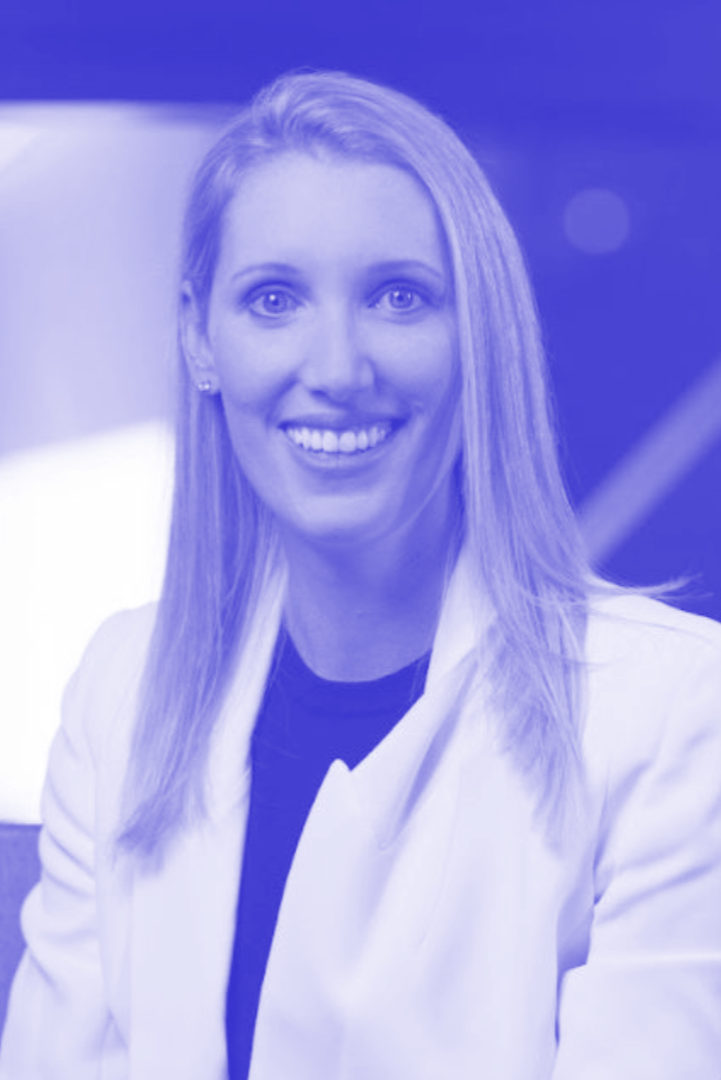 A woman with blonde hair, smiling, wearing a white blazer and a black shirt, in a professional setting.