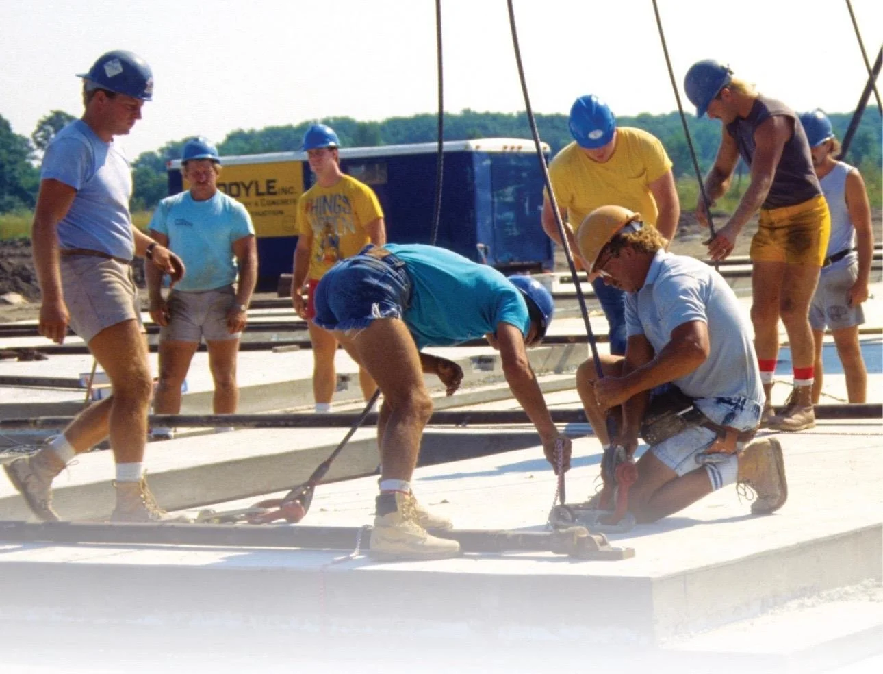 Construction workers with safety helmets installing large concrete panels on a building site.