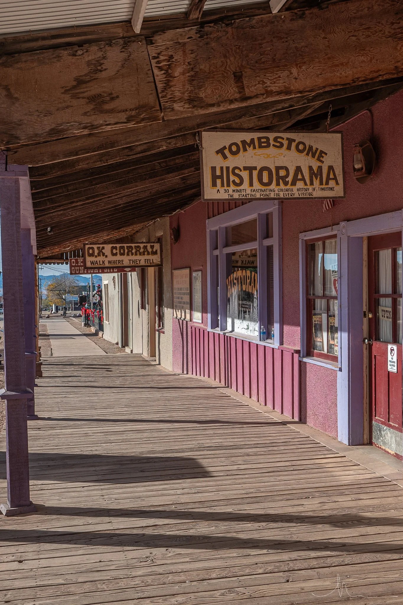 Downtown Main Street with wooden sidewalk, colorful storefronts, and signs for Tombstone Historama and O.K. Corral.