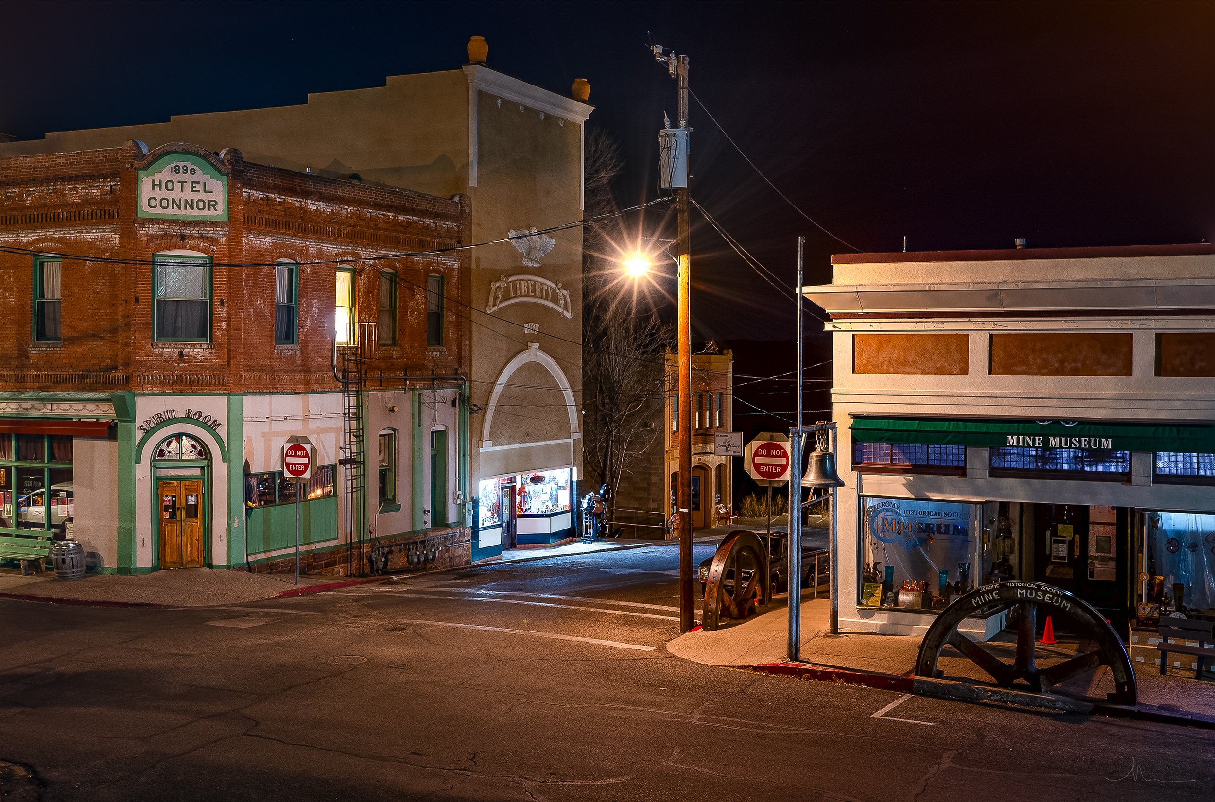 Nighttime view of a small town street with historic buildings, a hotel labeled 'Hotel Connor,' a museum, and a lit lamp post.