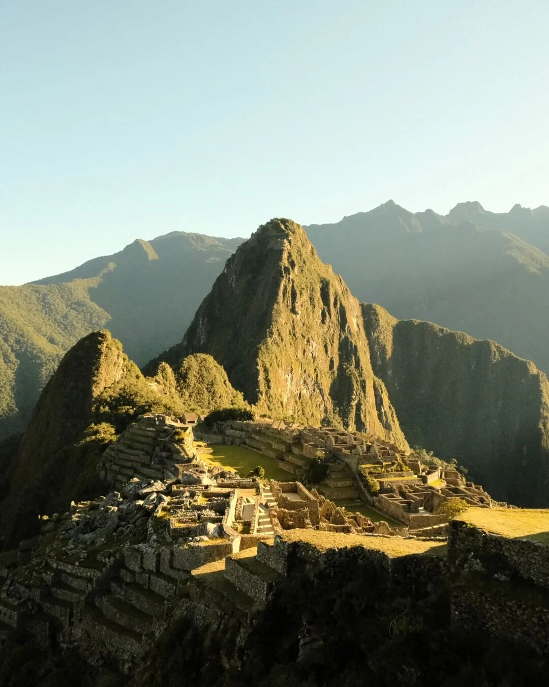 Ancient Incan ruins on a hillside with a mountain in the background, at Machu Picchu, Peru.