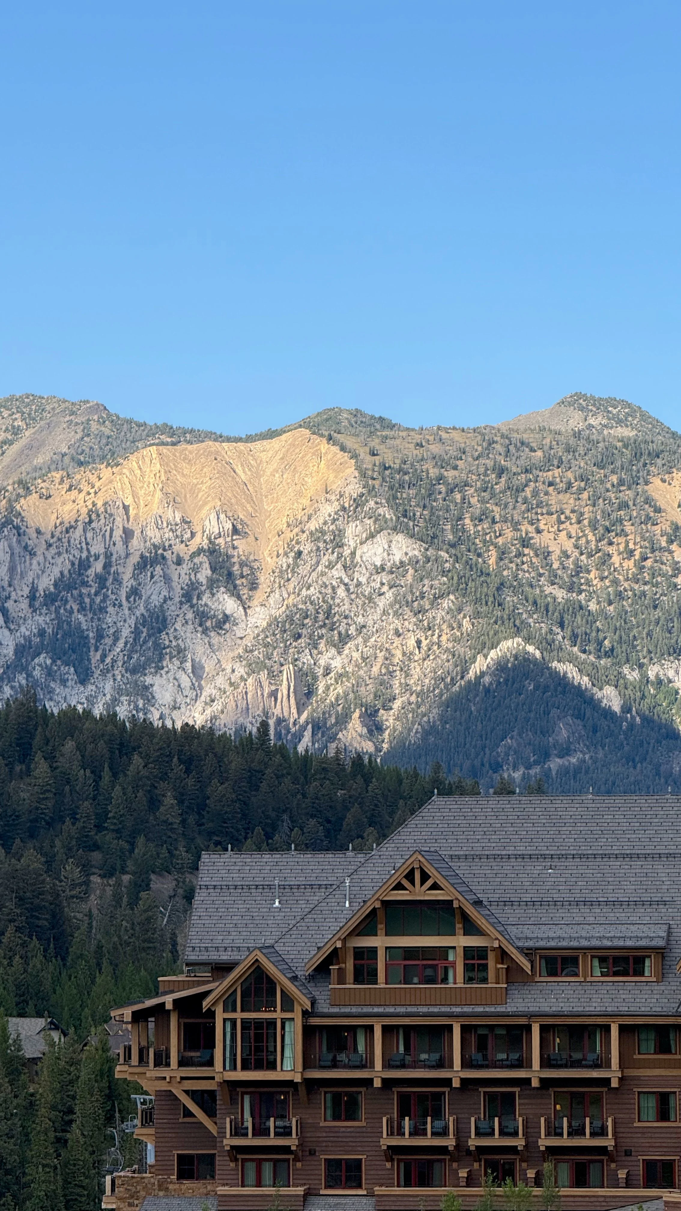 Mountain with trees and a roofed lodge in the foreground, a viewpoint from the Montage Big Sky.