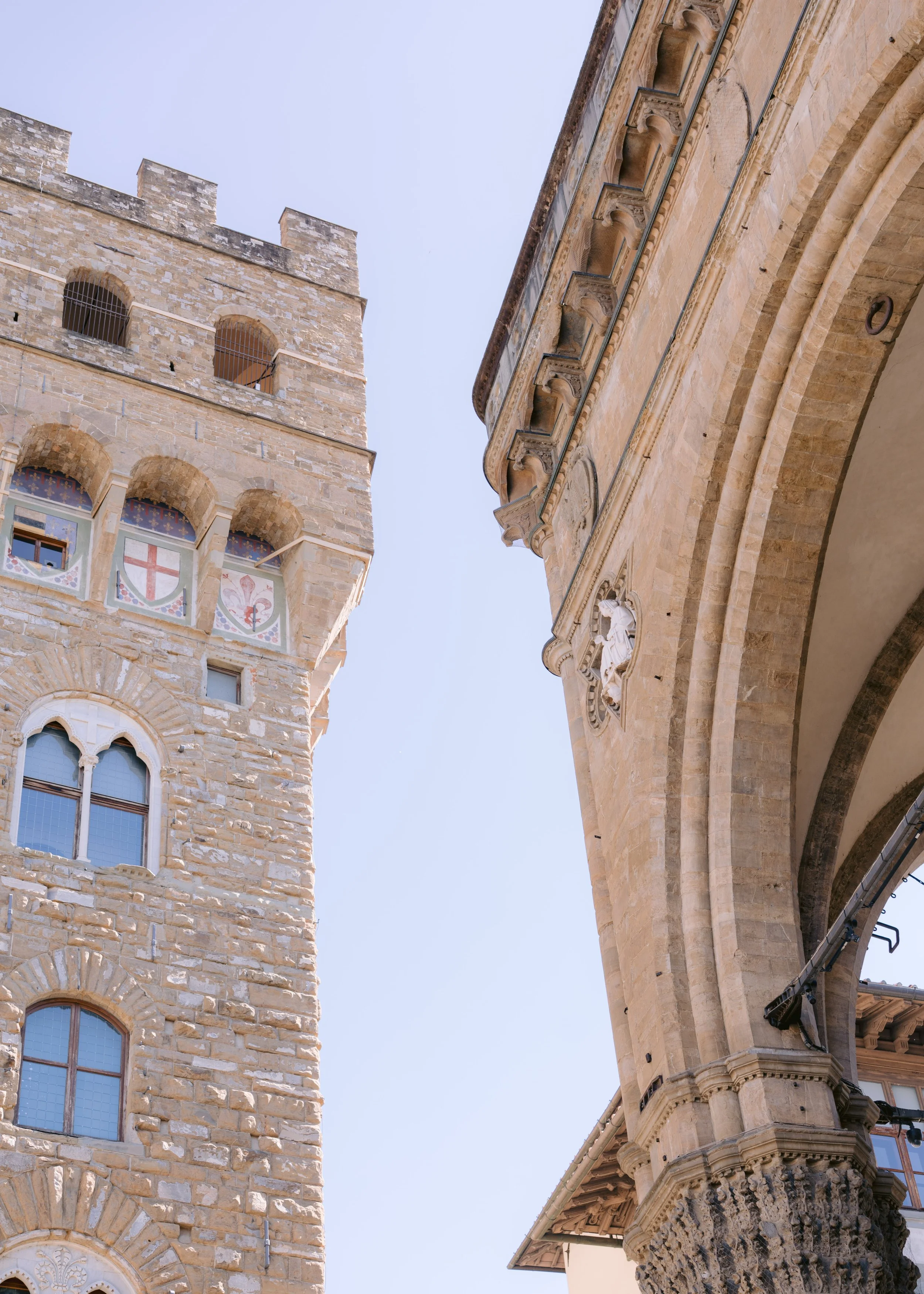 A low-angle view of historic stone buildings and architectural details under a clear sky.