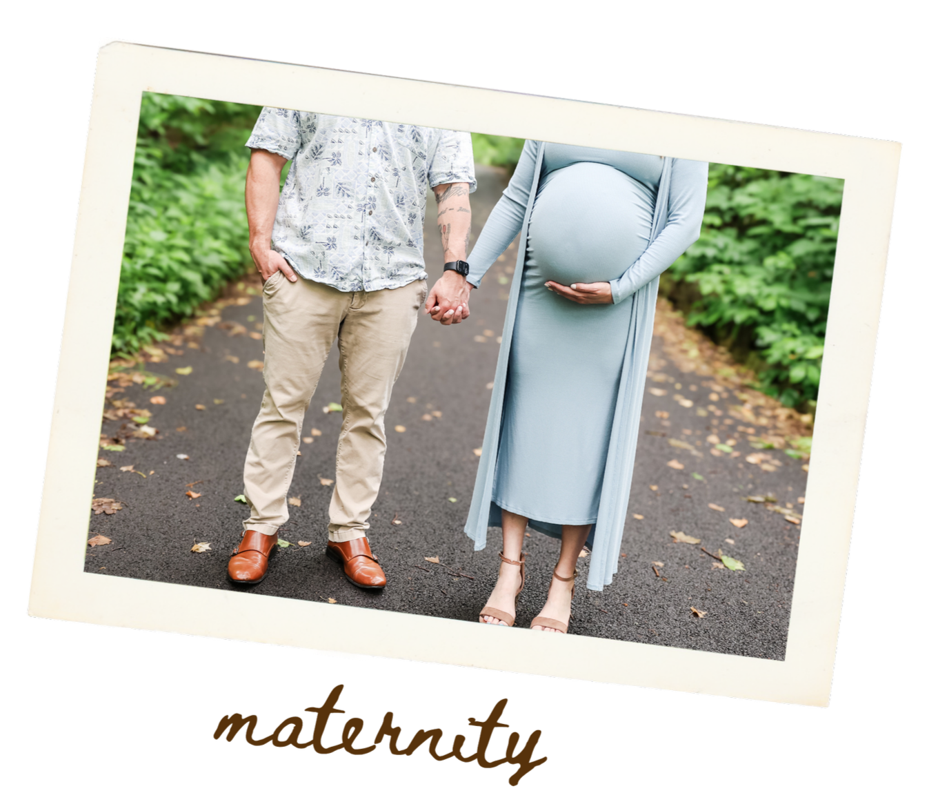 A pregnant woman and a man holding hands on a walking path in a park, with lush green foliage around them.