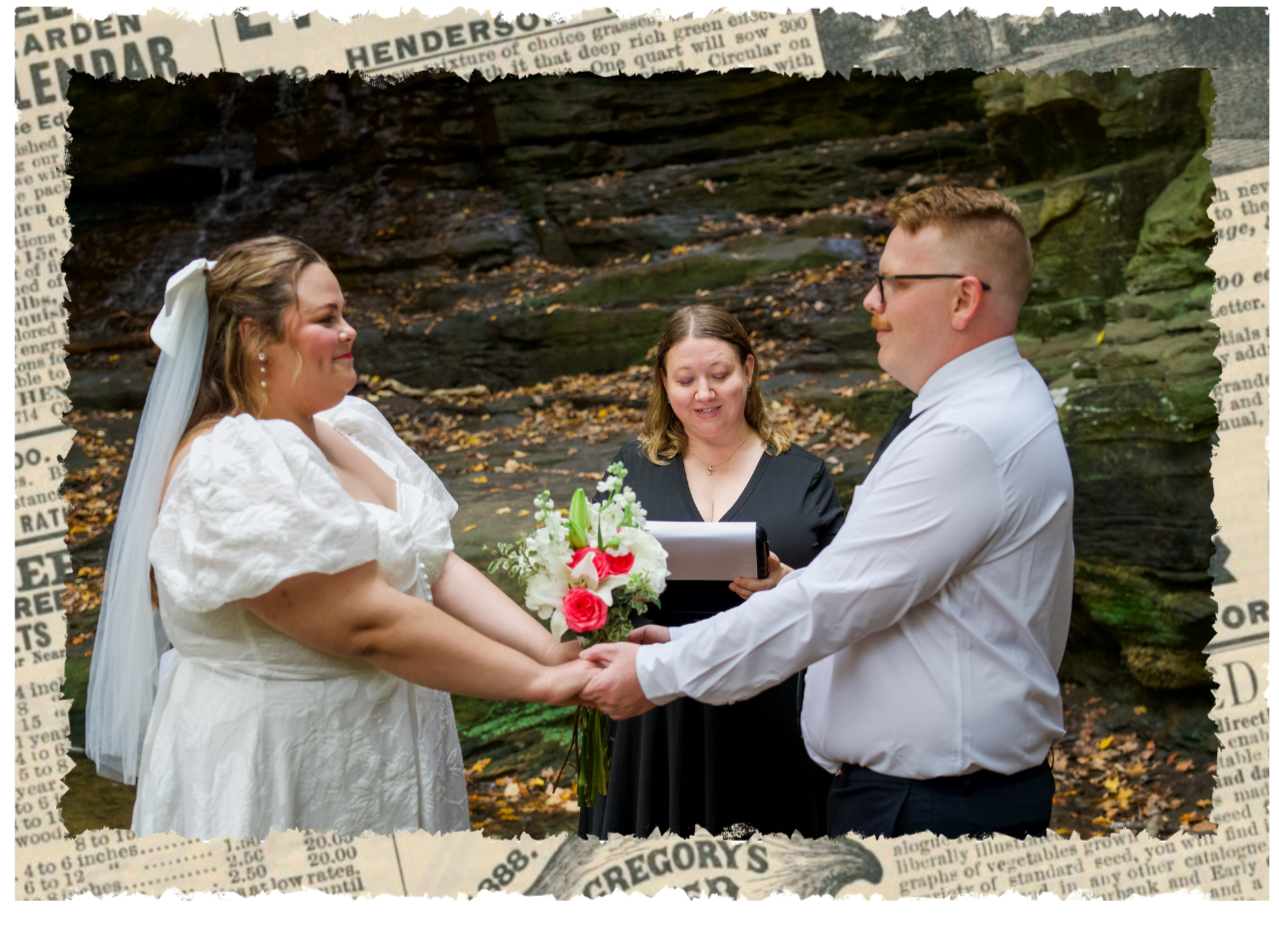 A couple getting married outdoors in front of a rocky, wooded background, holding hands, with an officiant reading from a book and holding a bouquet of white and pink flowers.