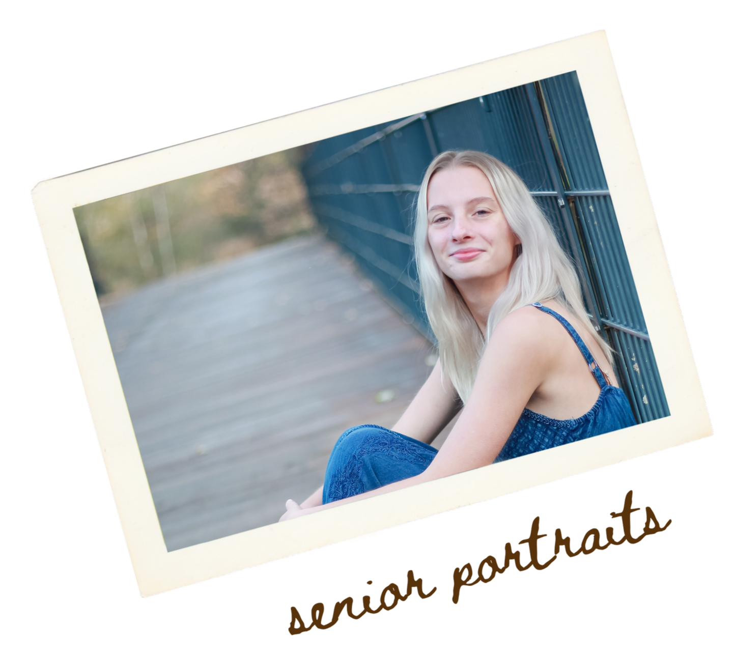 A young woman with long blonde hair sitting outdoors. She is leaning against a blue railing and wearing a blue sleeveless top. The background shows a blurry outdoor scene with trees and pavement.