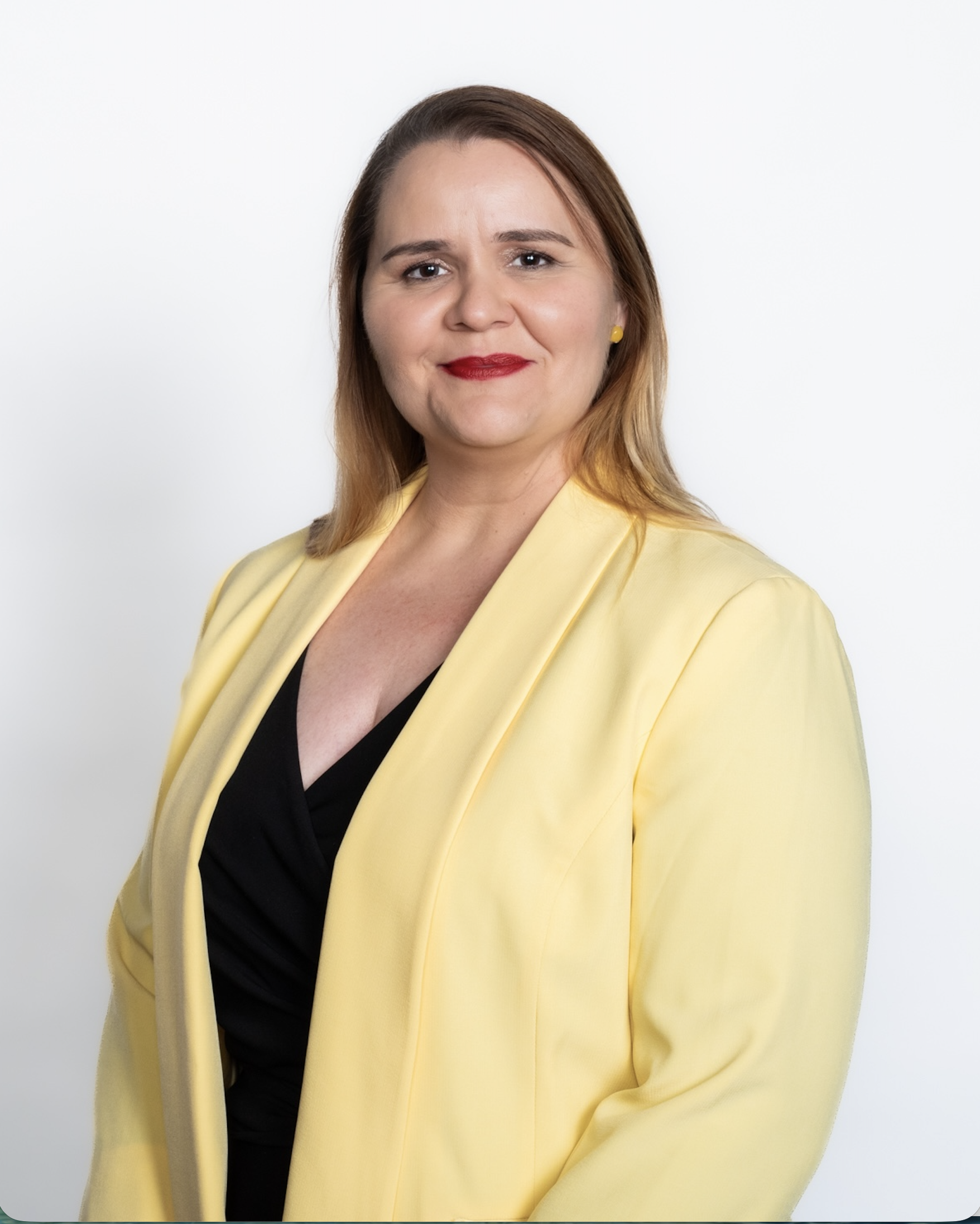 Photo of Samantha smiling at the camera, wearing a pale yellow blazer over a black top.