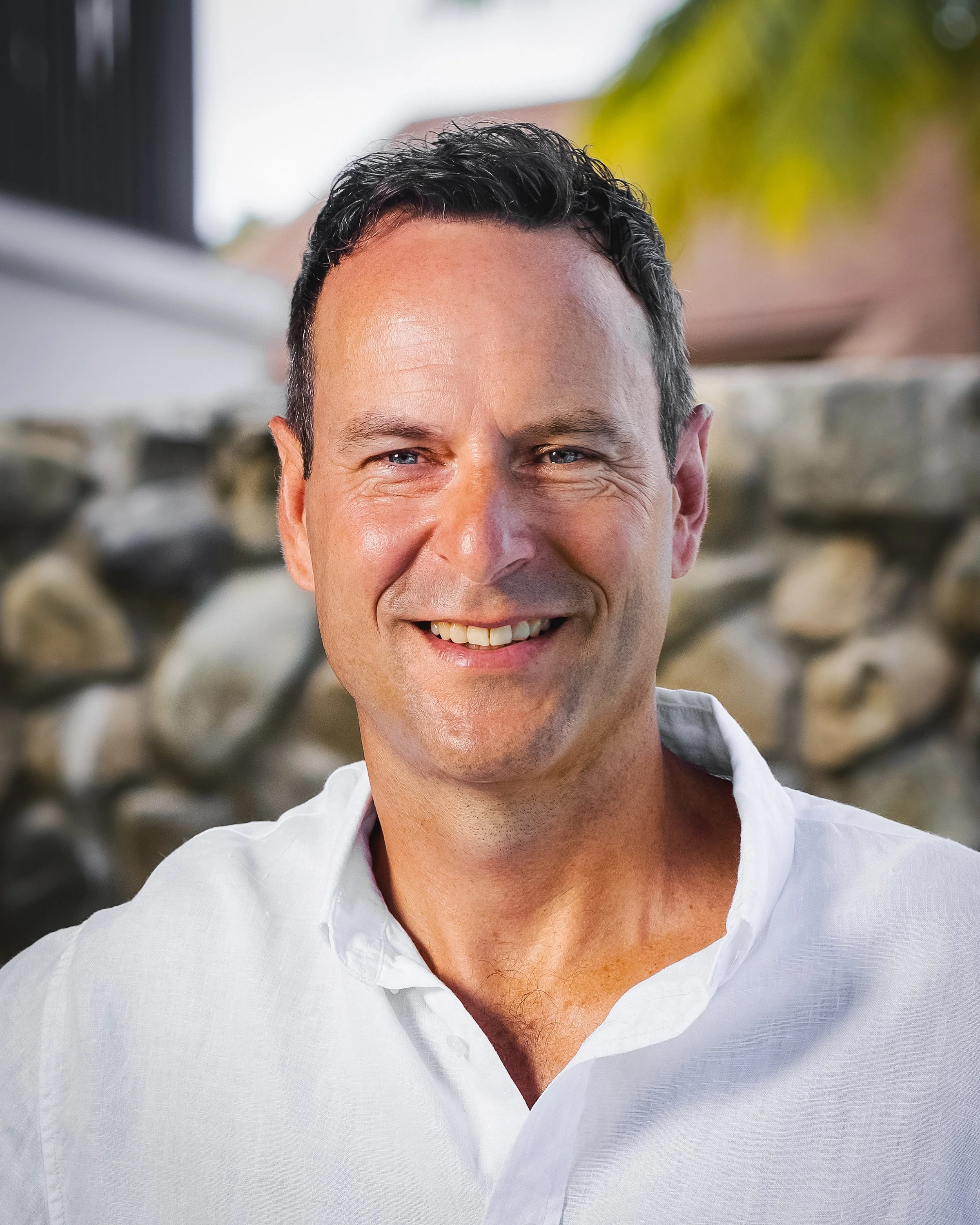 Photo of Brent smiling at the camera. He has short dark hair, and wears a white collared shirt.