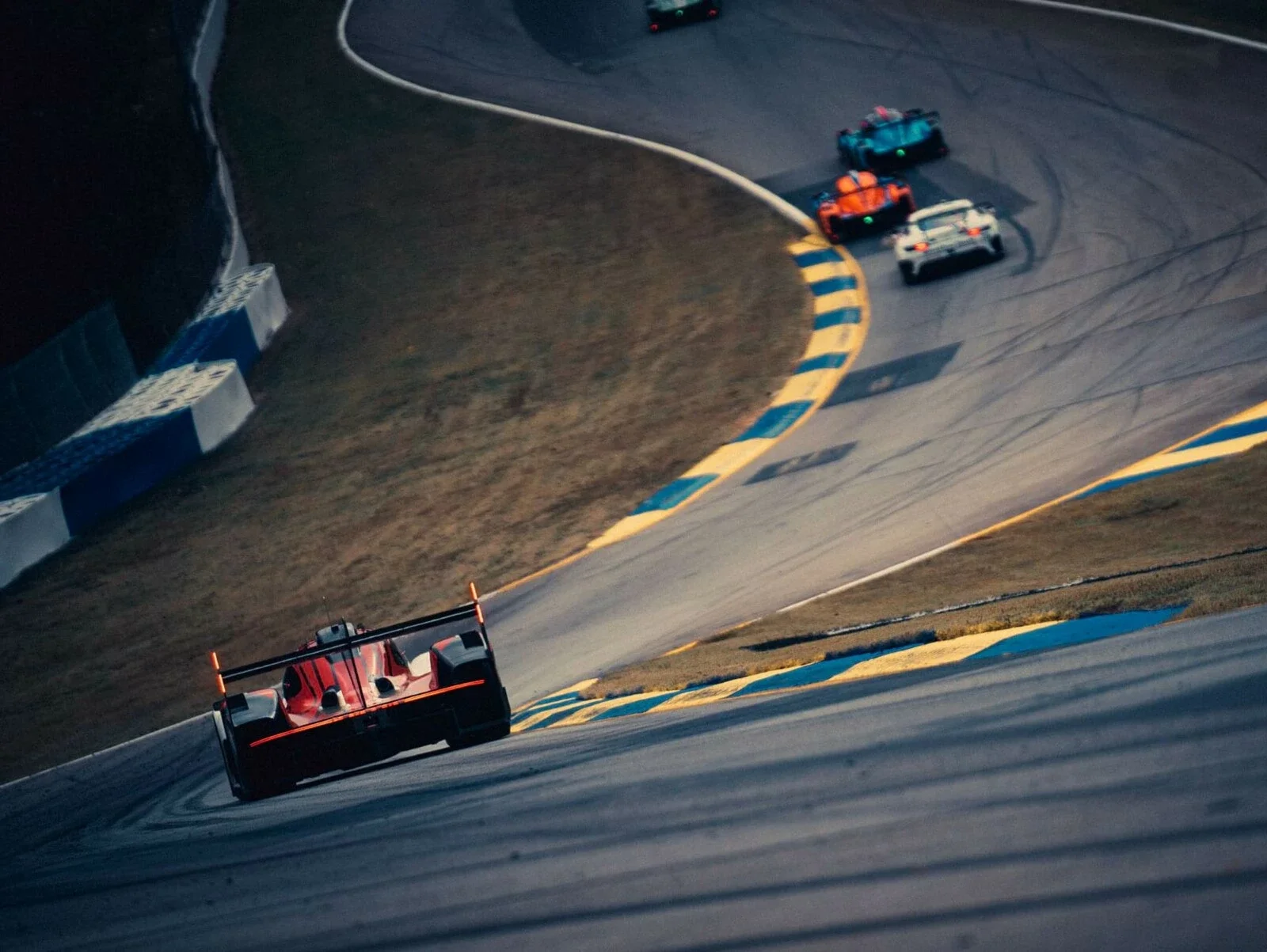 Racing cars on a winding track, with one car in foreground and three cars ahead near a curve.