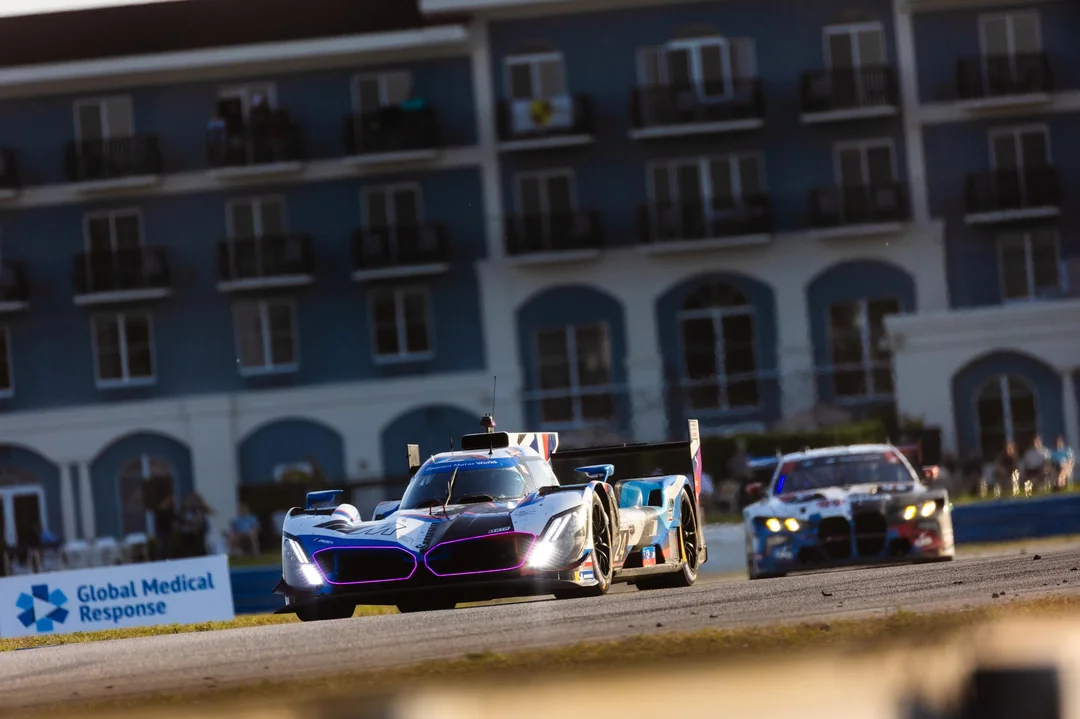 Two race cars on a track, with a building in the background, during a motorsport event.