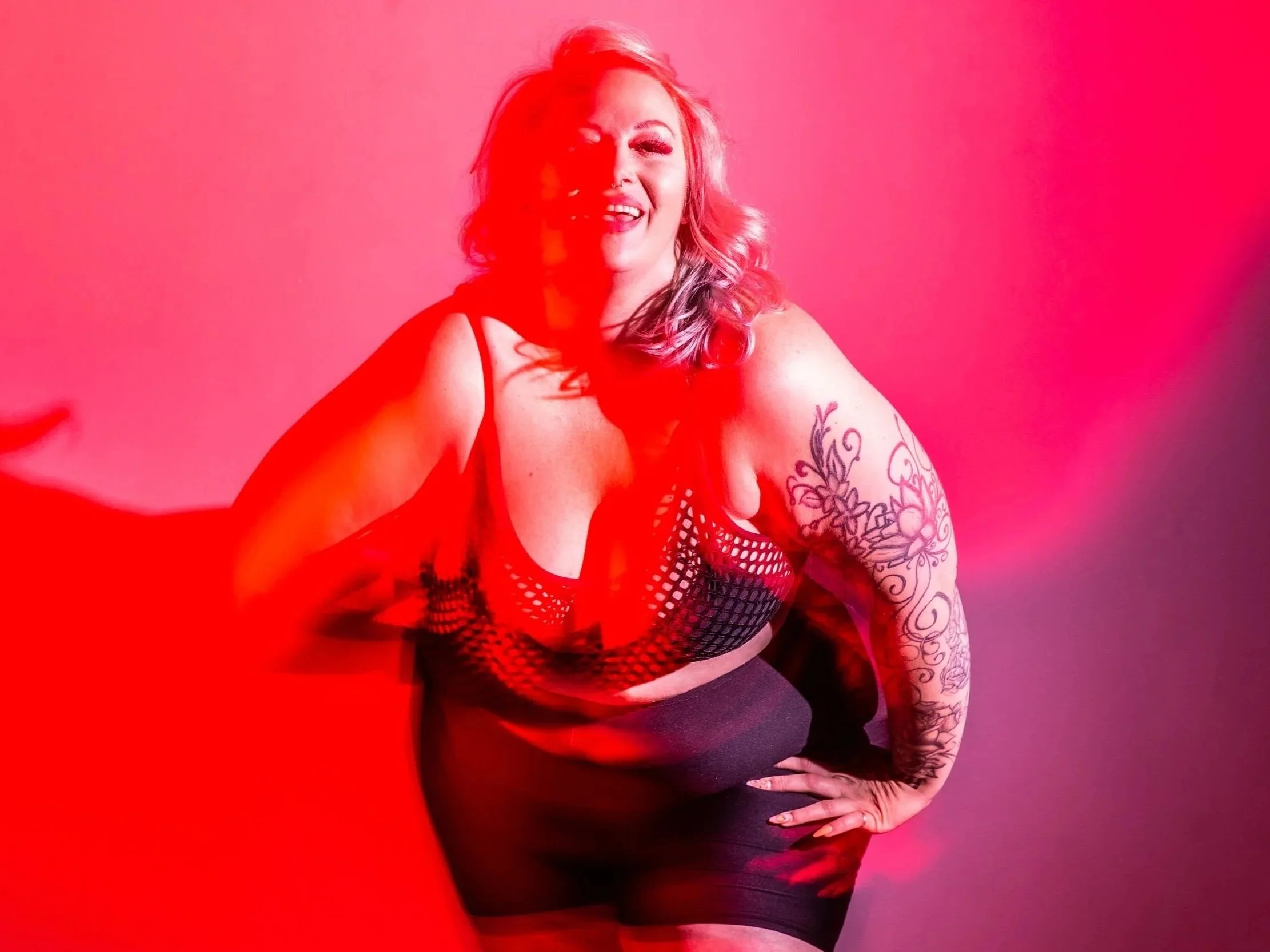 plus size dancer poses and laughs casting red shadows