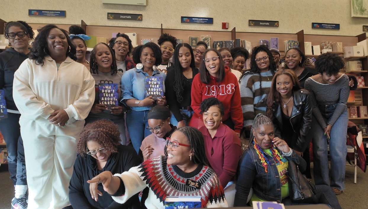 Black Lit. book club members in a bookstore or library, smiling and posing for a photo.