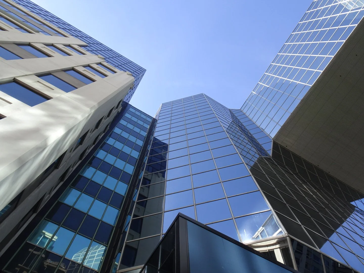 Looking up at modern skyscrapers with glass facades reflecting the sky.
