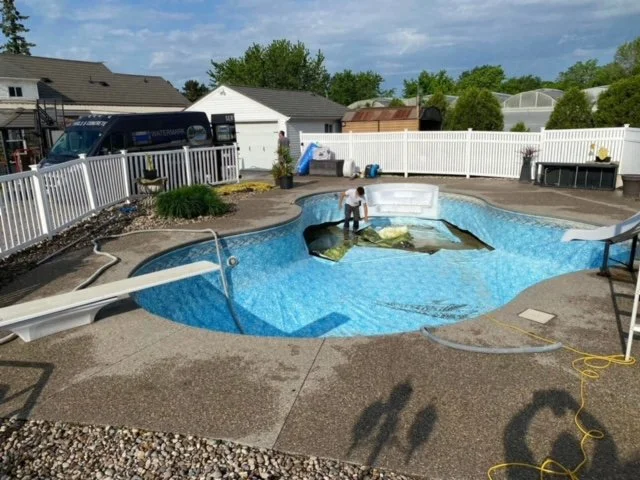 A swimming pool with an old pool liner being removed by a pool technician.