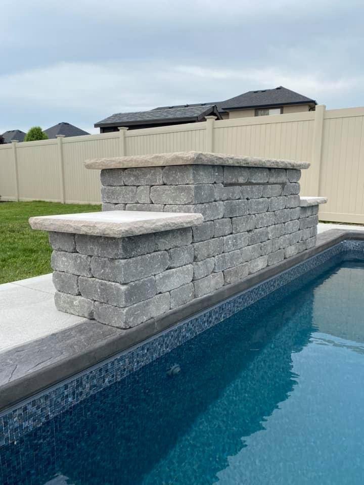 Close-up of a grey stone water feature on a inground swimming pool.