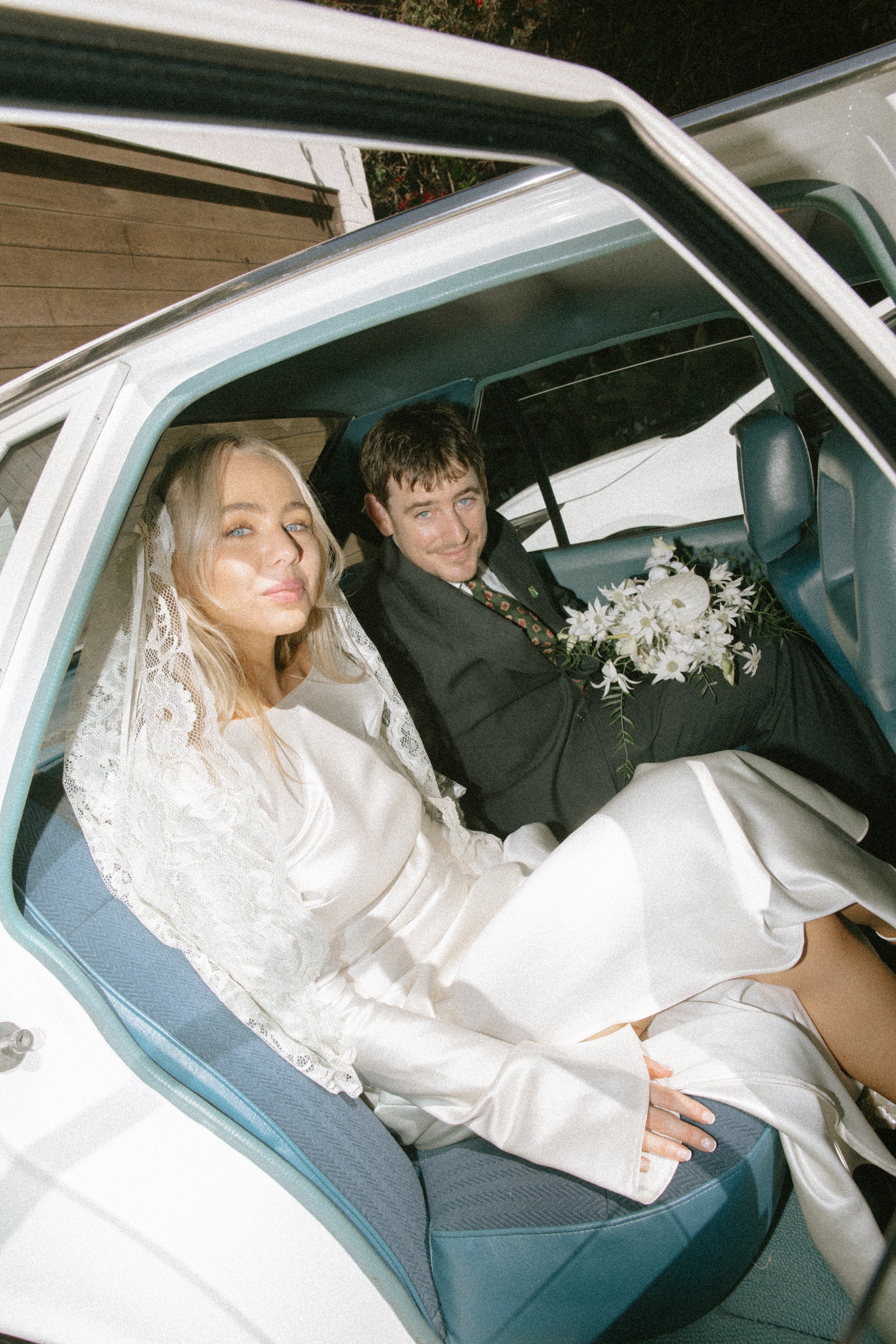 Married couple sit in the back of a vintage car
