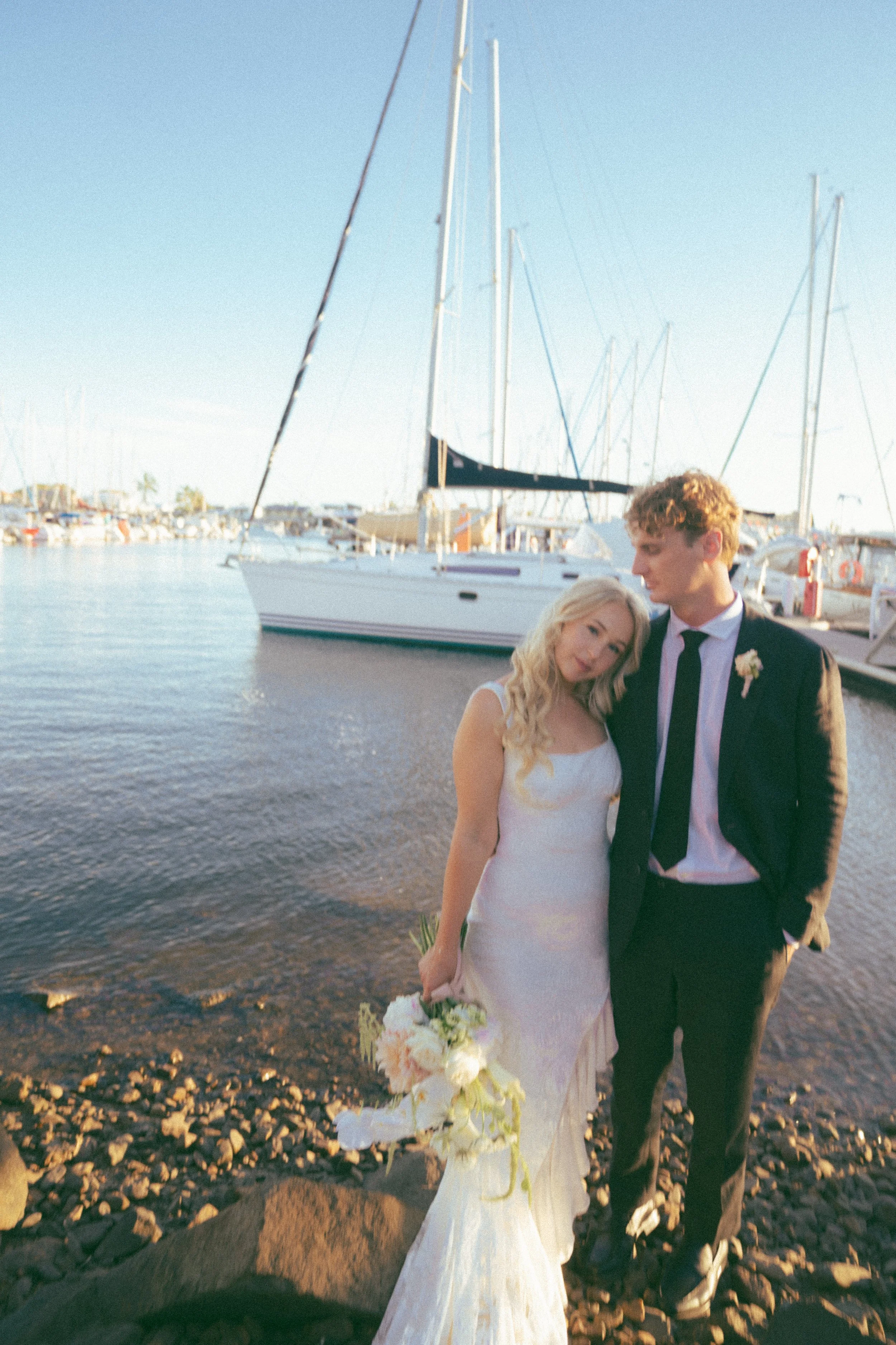 Married couple posing in front of boat and ocean