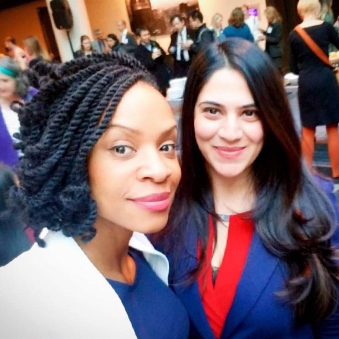 Rinki Varindani Desai taking a selfie at a social event, with a crowded room of people in the background.