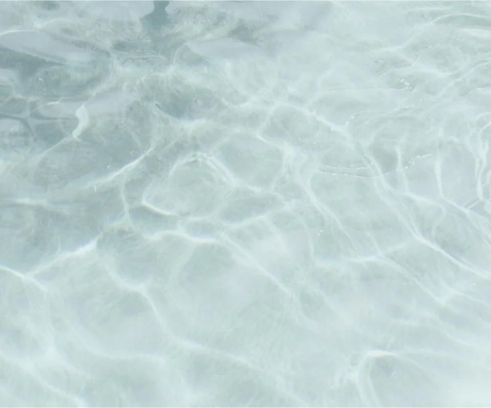 Close-up of clear, shallow water with sunlight reflections creating patterns.