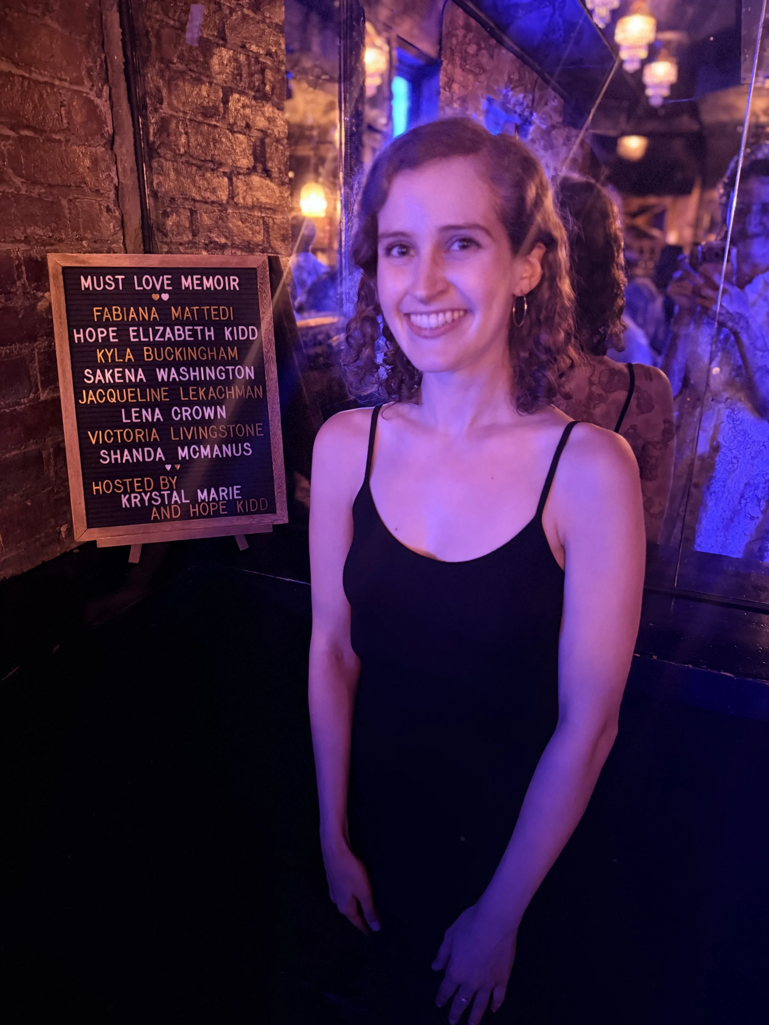 Jacqueline stands next to a sign with all the readers' names. 