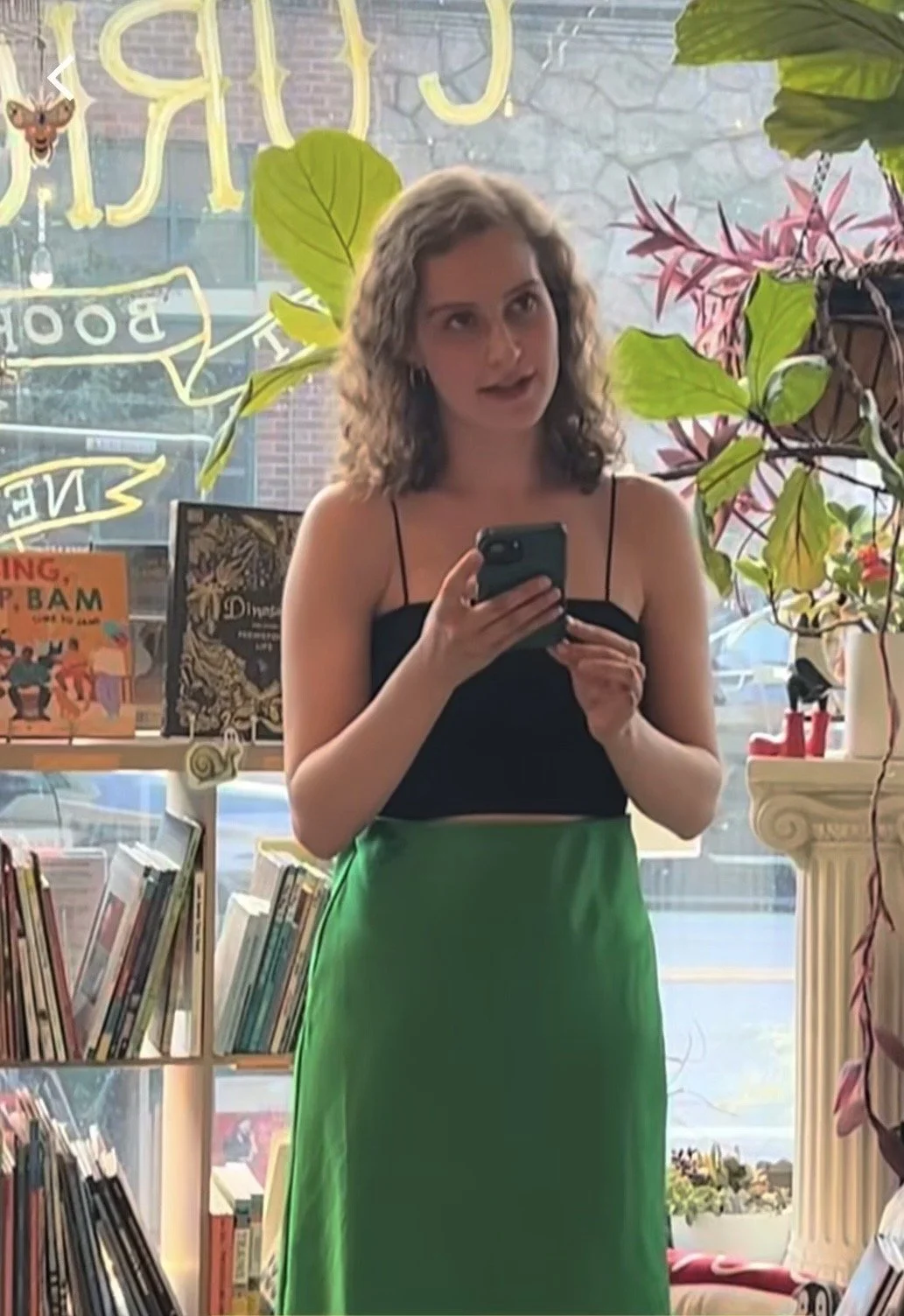 Jacqueline stands in front of the bookstore's front window, reading her piece.