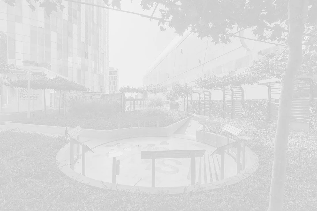 Outdoor urban courtyard with plants, trees, and seating areas surrounded by modern high-rise buildings.