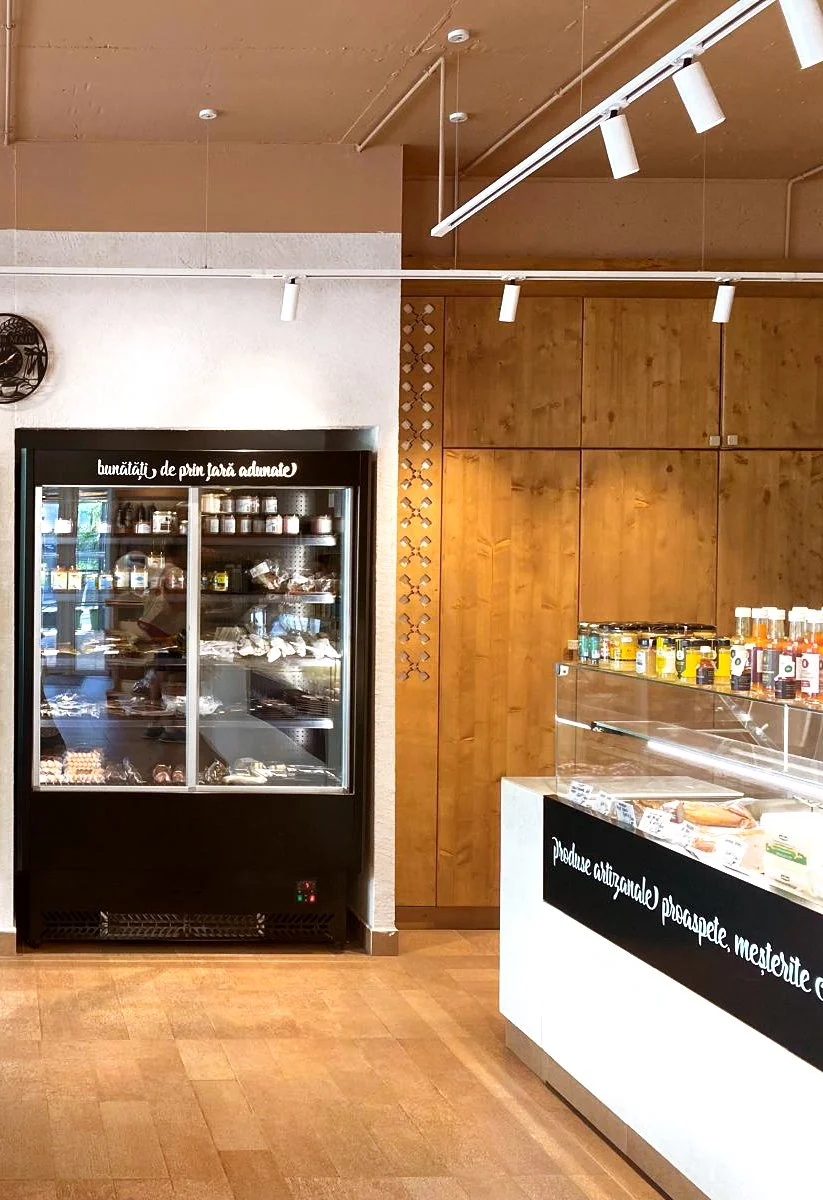 Vitrină frigorifică și zonă de servire integrate într-un spațiu horeca cu finisaje din lemn