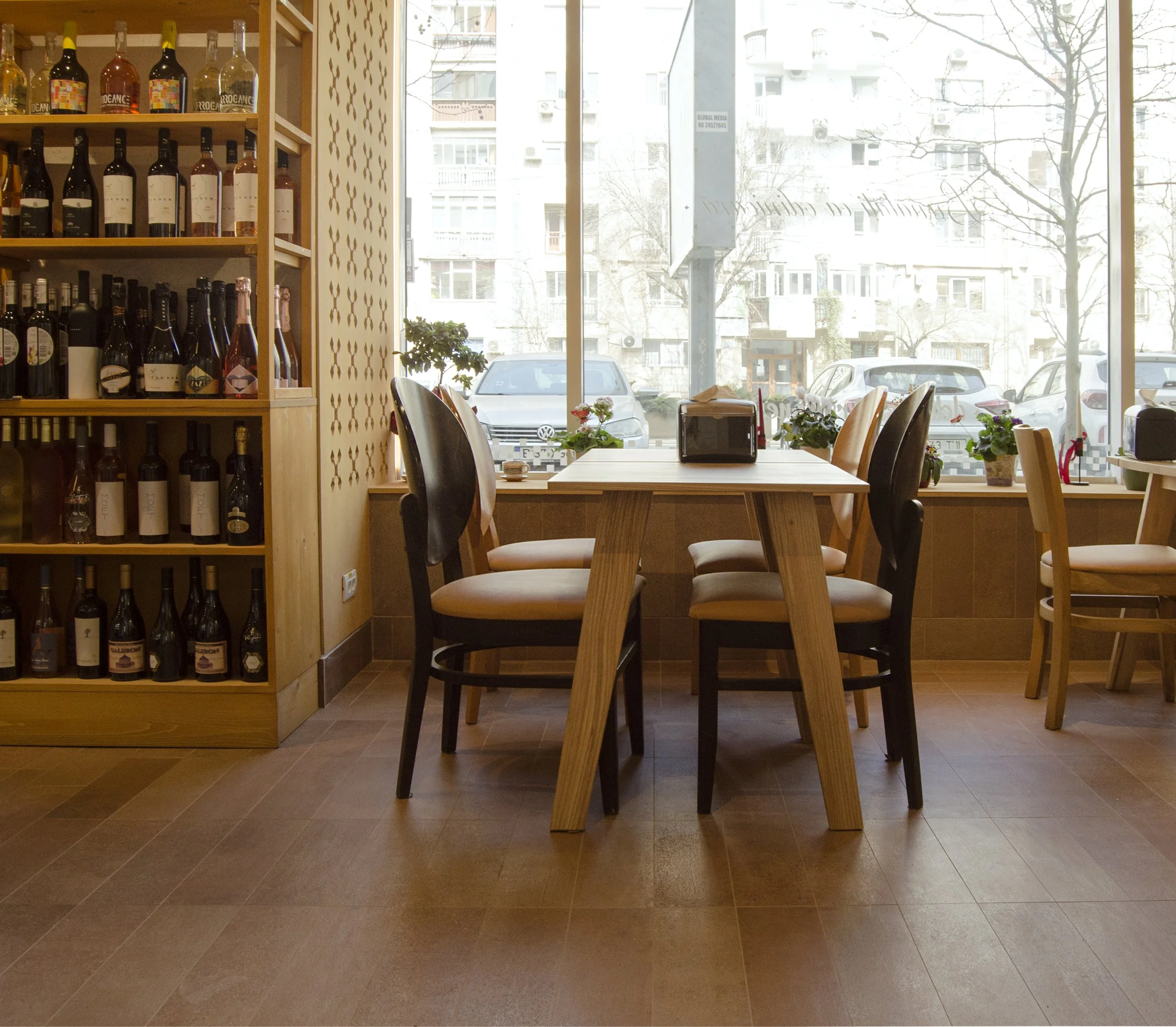 Zonă de seating în spațiu horeca cu mobilier din lemn și expunere produse pe rafturi modulare