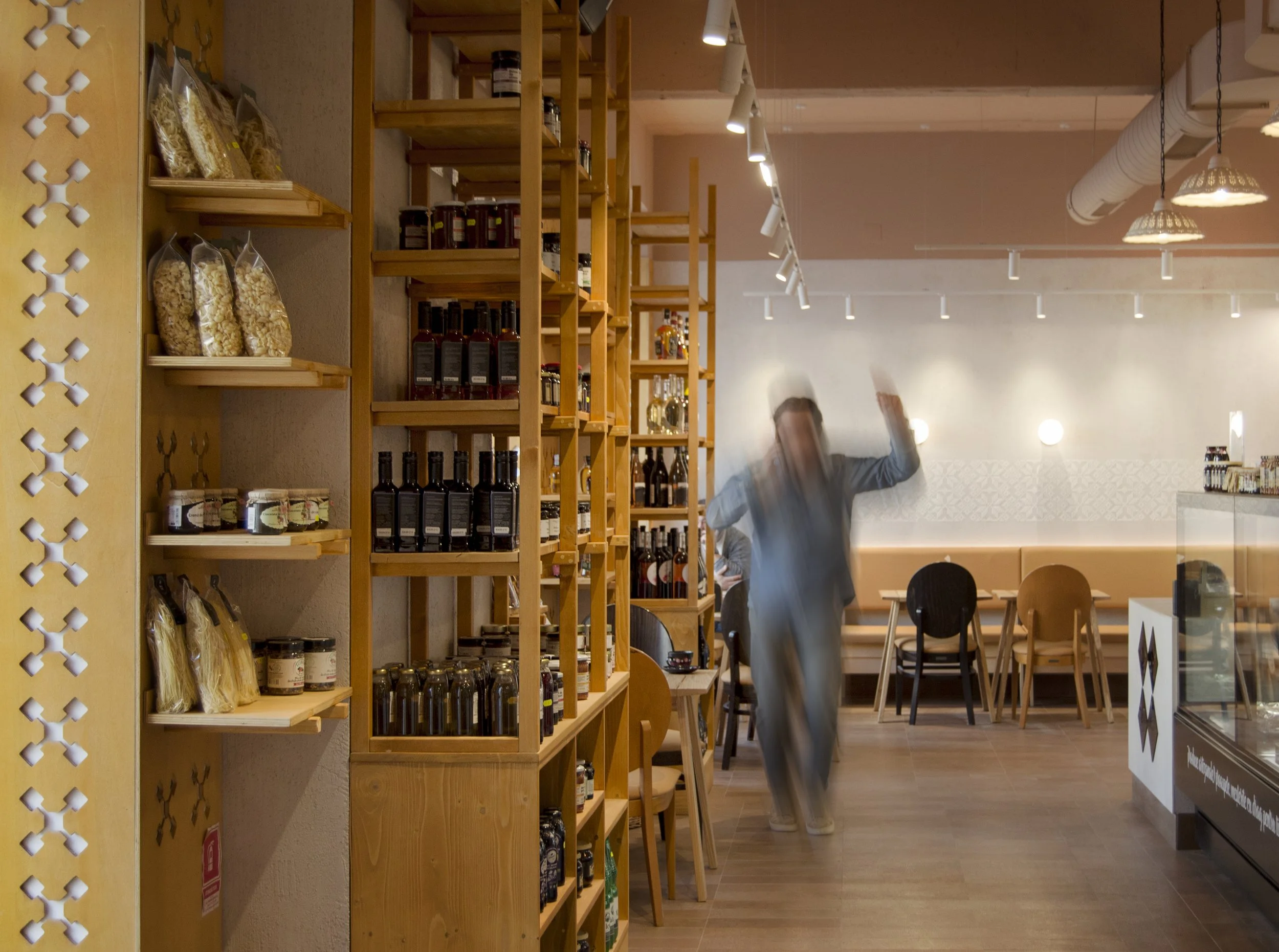 Spațiu horeca ma.iu organizat cu etajere modulare din lemn și zonă de circulație centrală