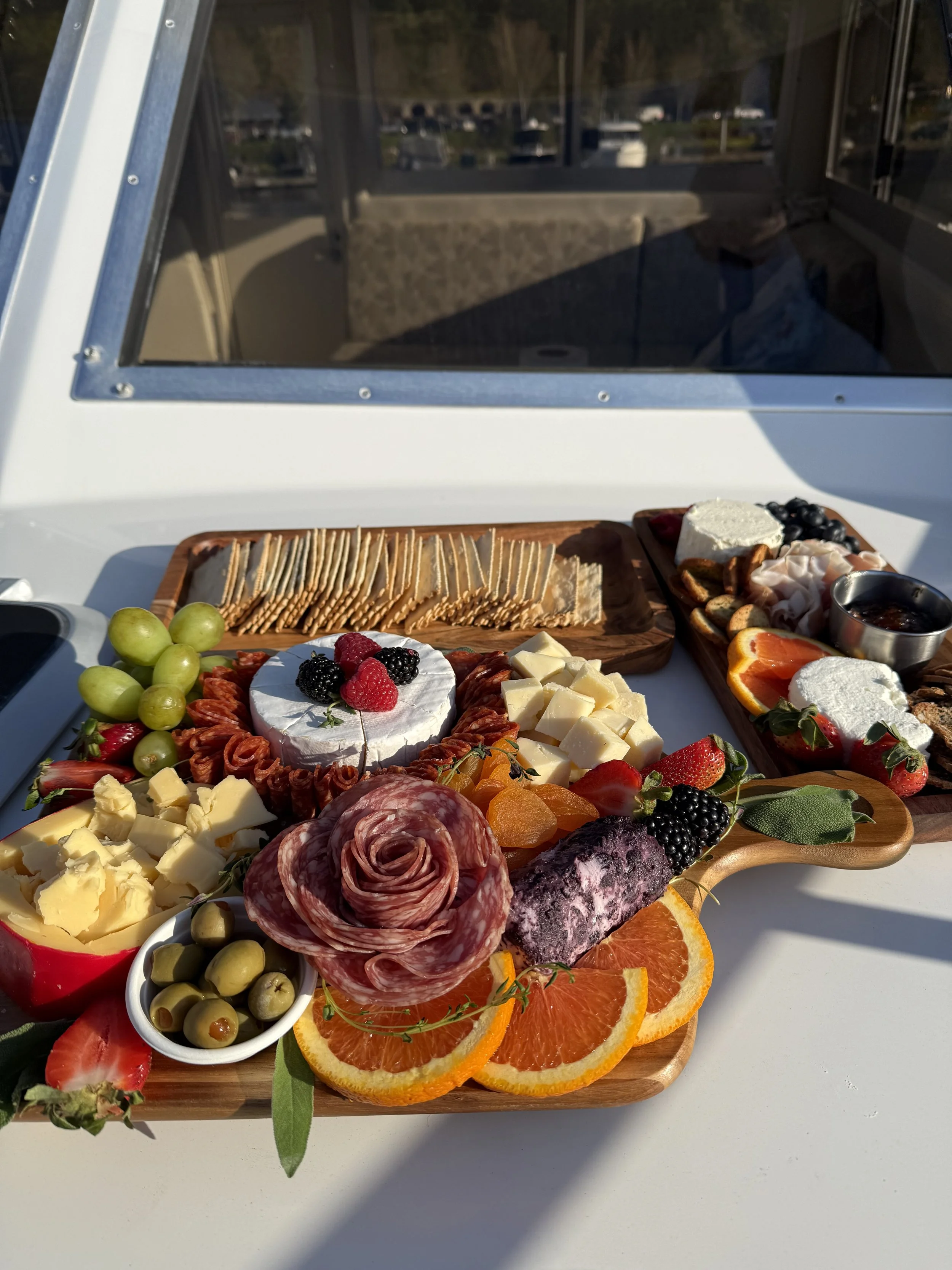 Assorted cheese, fruits, crackers, and charcuterie spread on wooden platters with berries, oranges, grapes, strawberries, and cured meats, set on a table.