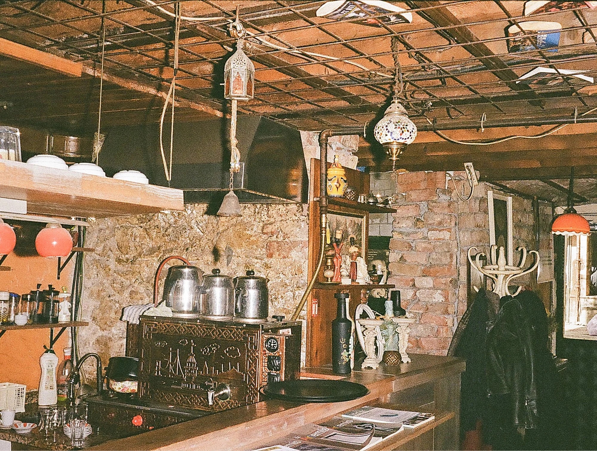 Interior of a rustic kitchen with exposed brick walls, open shelving, and vintage decor including lanterns and statues.