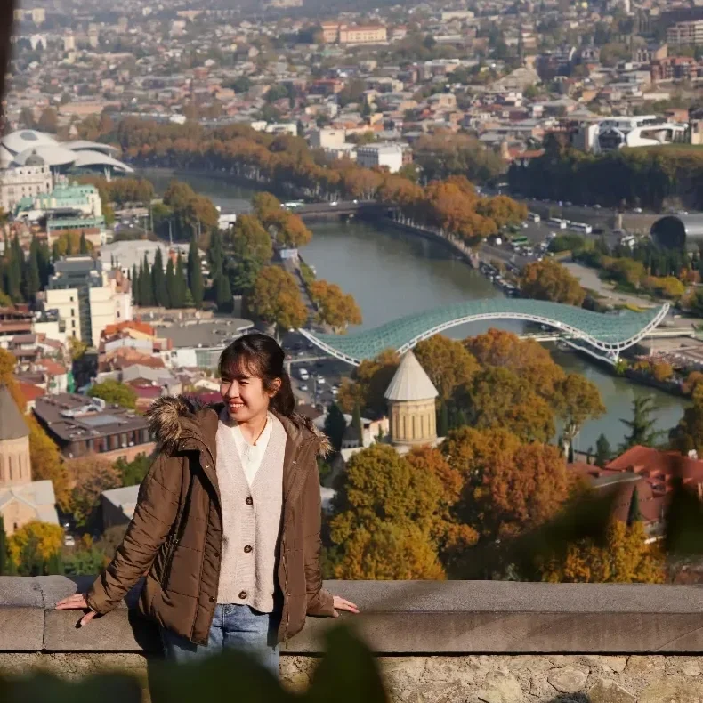 Scenic view of a lake surrounded by green hills and mountains with cloudy sky