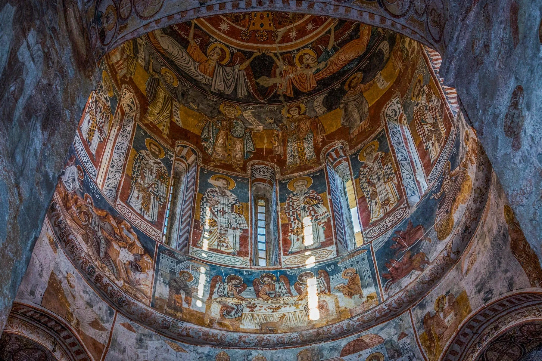 Colorful religious frescoes on a domed ceiling depicting saints and biblical scenes.