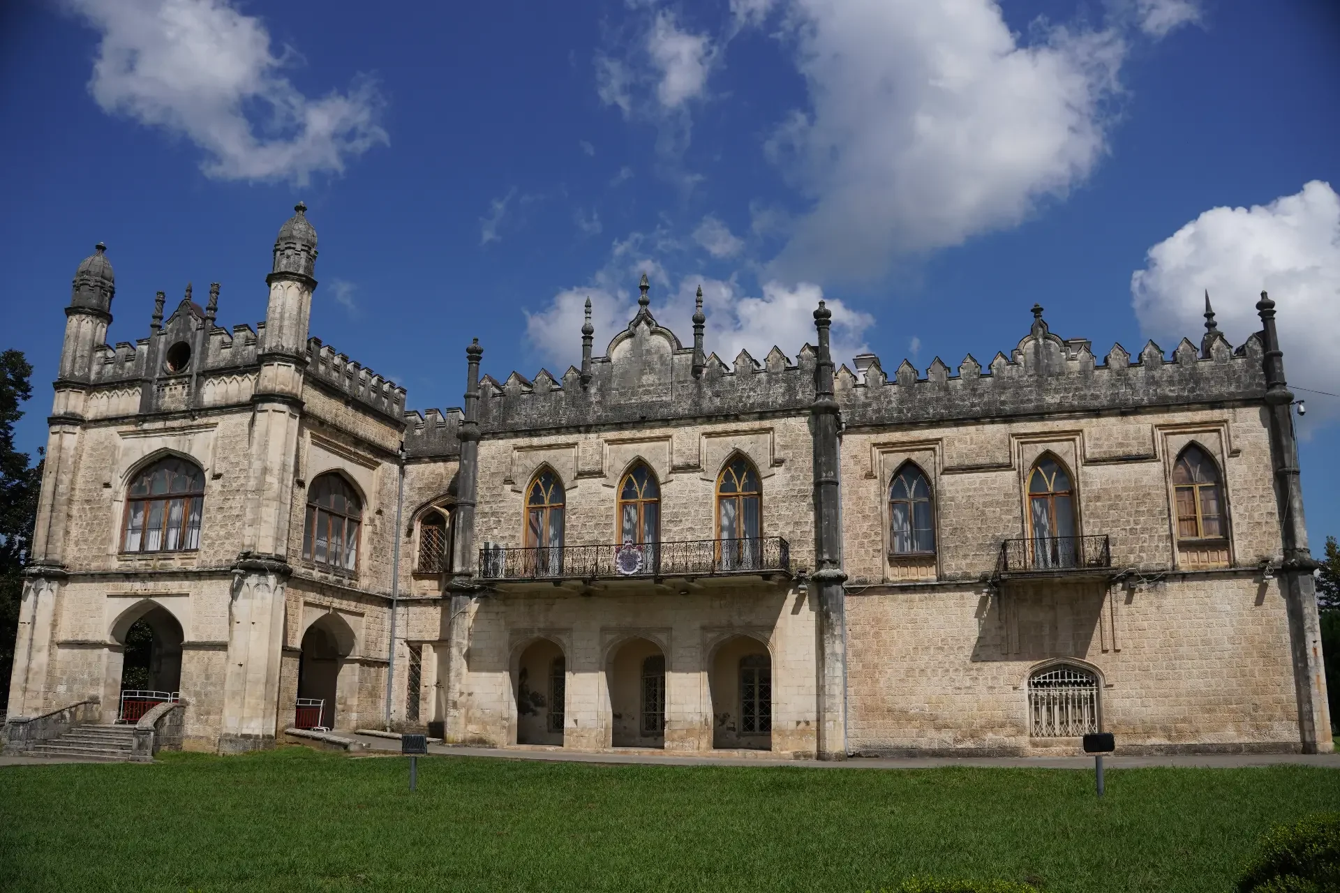 A historic stone castle with gothic architectural features under a partly cloudy blue sky.