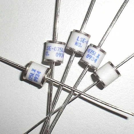 Multiple cylindrical electronic components with metal leads laid on a white surface.