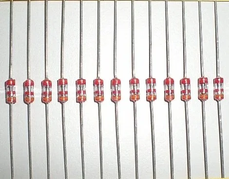 Close-up of multiple red and clear light-emitting diodes (LEDs) arranged in a row on a white background.