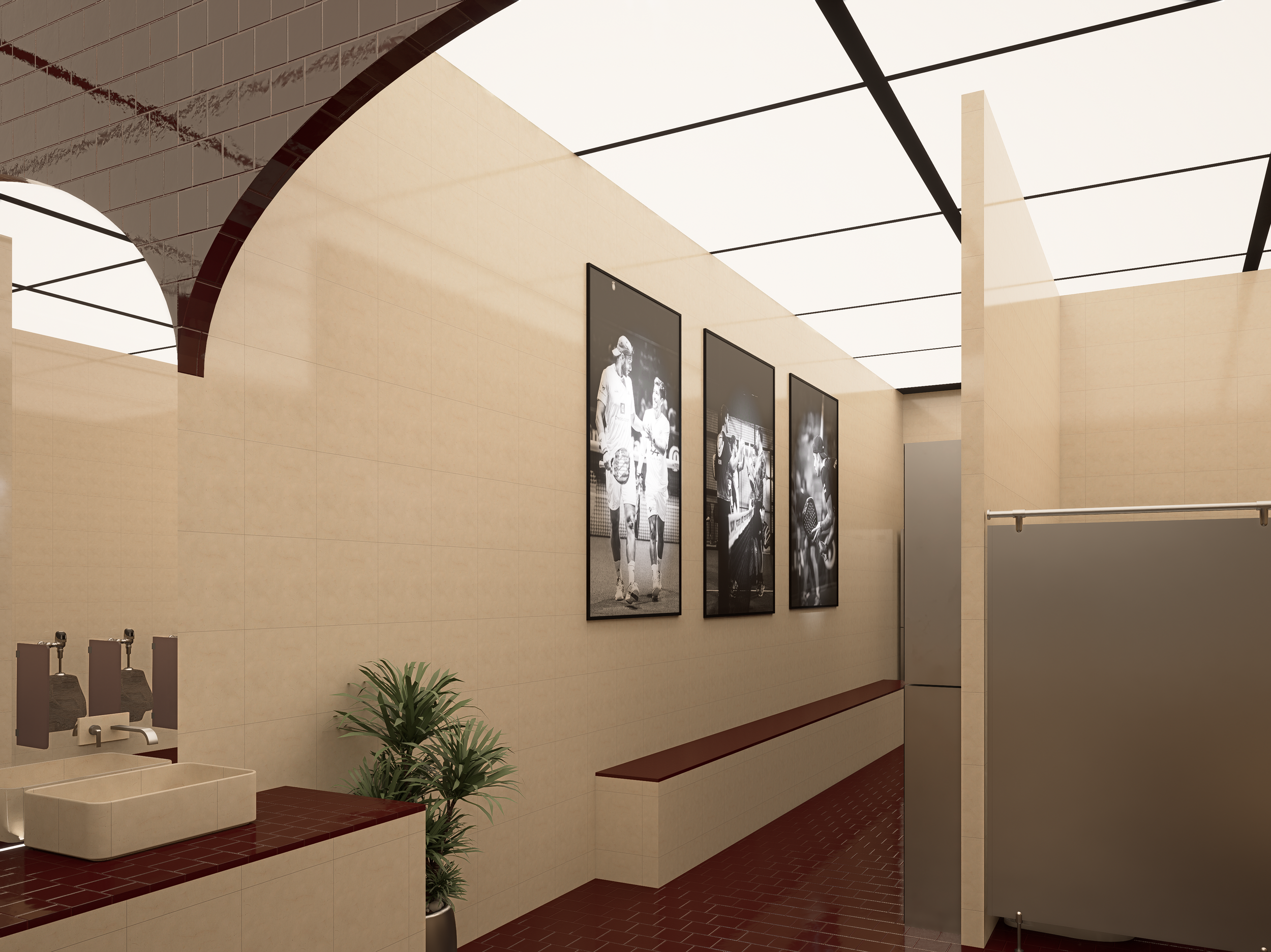 Public restroom with framed black and white photographs on beige tiled wall, plant in corner, sink with brown countertop, and privacy stall on right.