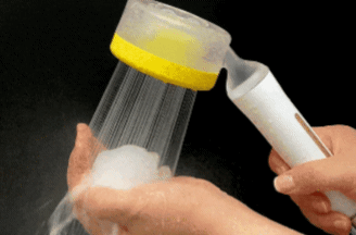 Person using a handheld milk frother to froth milk in a container