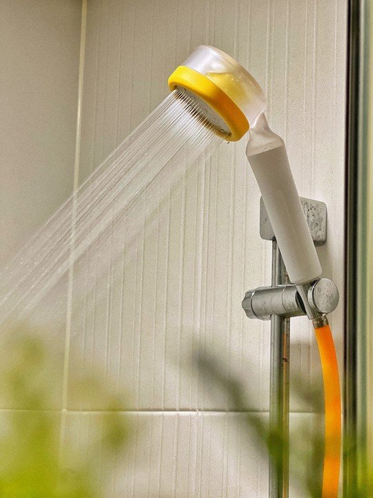 Shower head mounted on the wall with water flowing out.