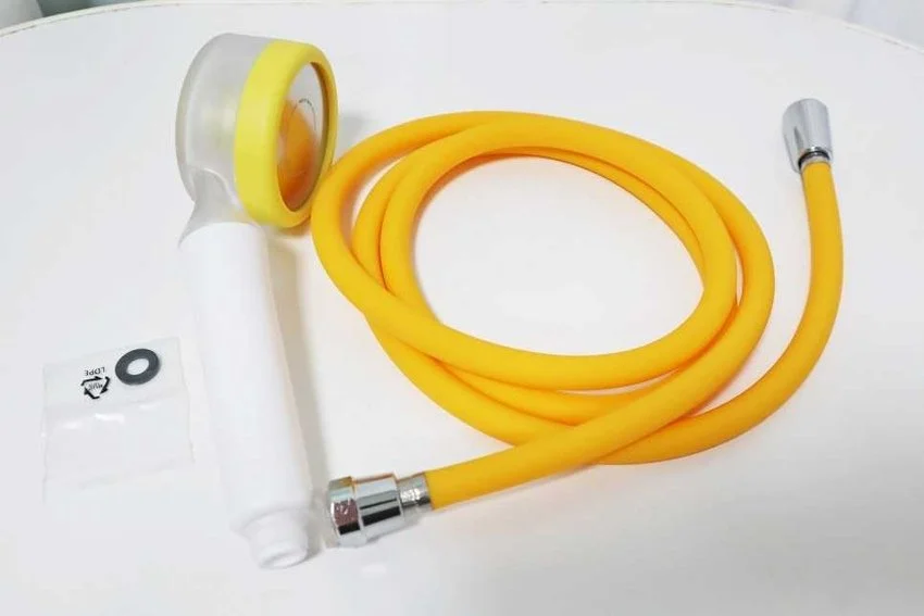 Yellow silicone nasal spray or nebulizer with a hose, a spray nozzle, and a small packet of O-rings on a white surface.