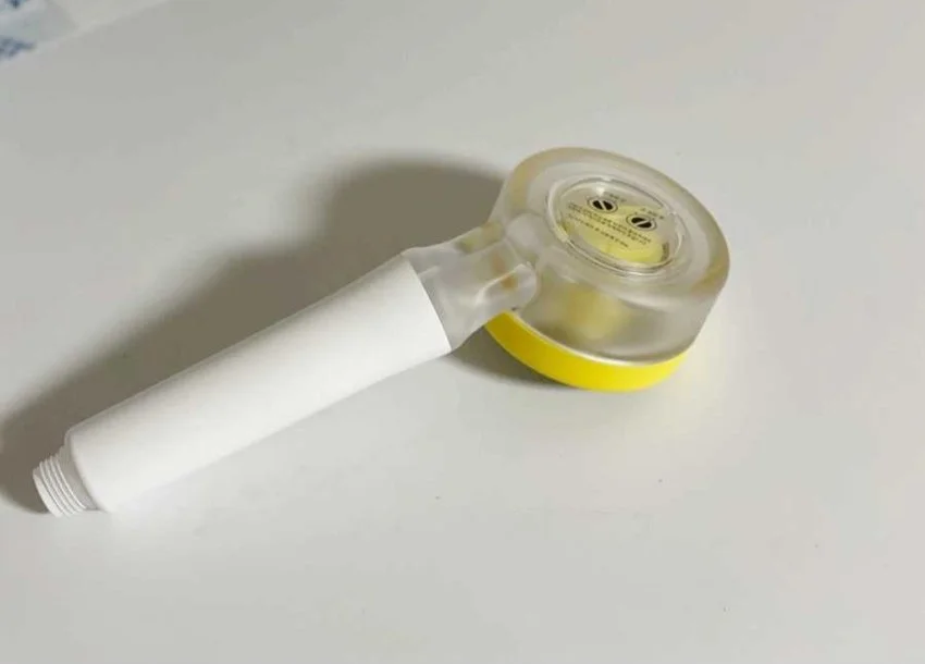 A roll of transparent adhesive tape with a yellow core lies on a white surface.