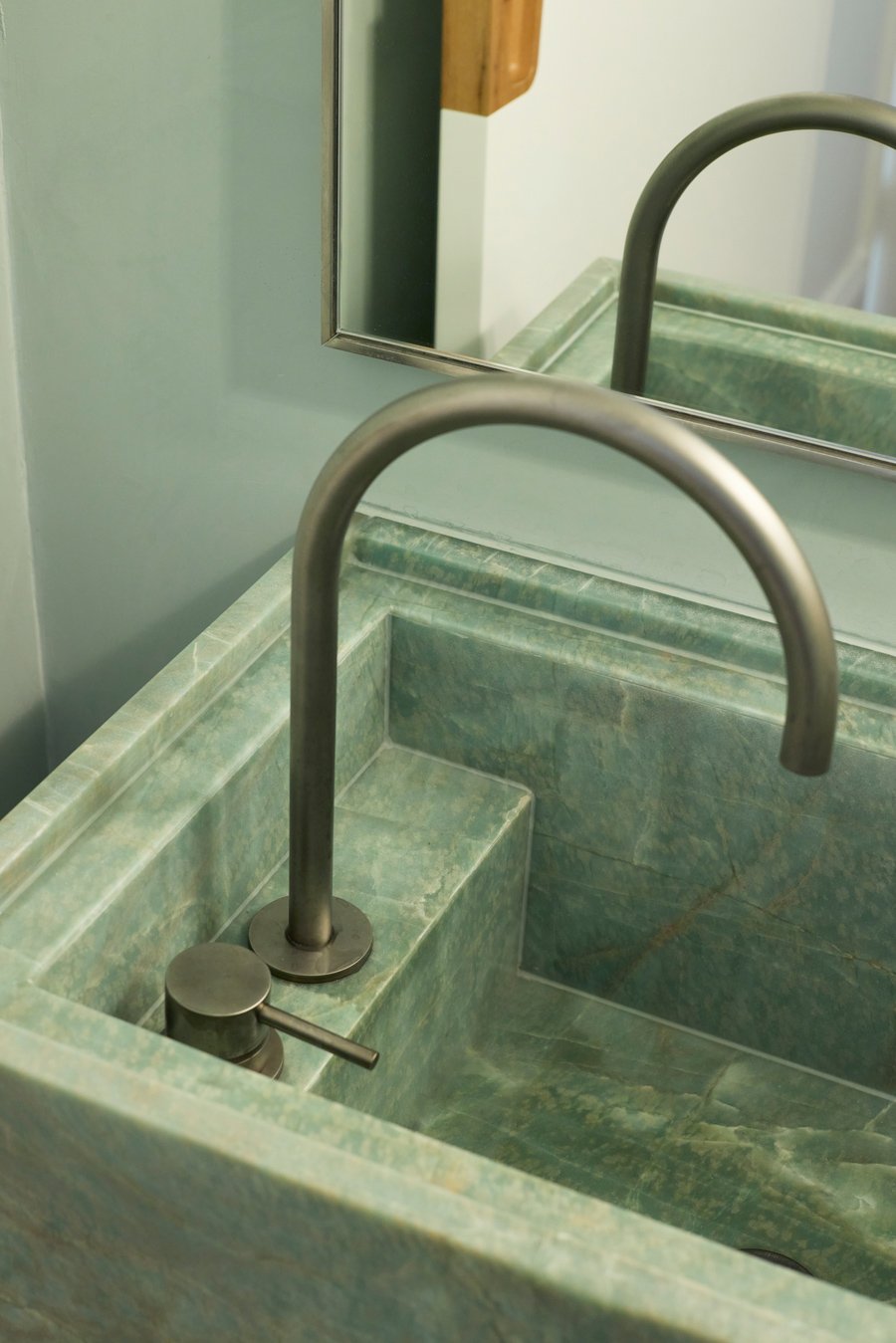 A marble sink with a silver faucet and a mirror in a bathroom.